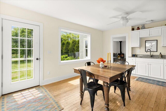 276 N Sedgwick Rd, Sedgwick, ME 04676 - dining area with light wood-style flooring, a wood stove, ceiling fan, and baseboards