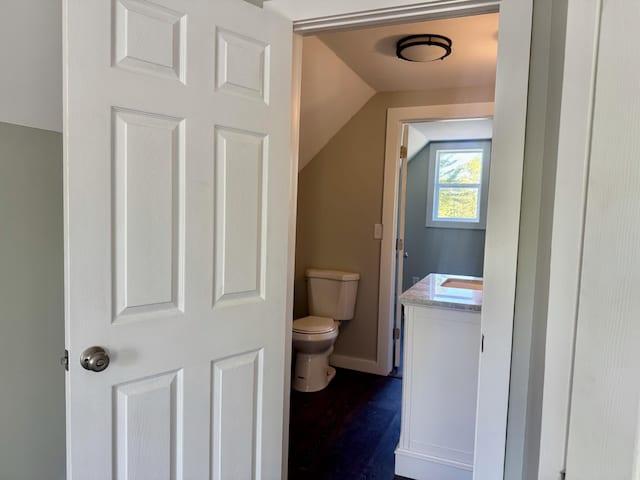 338 River Rd, Bucksport, ME 04416 - half bathroom featuring toilet, vanity, lofted ceiling, wood finished floors, and baseboards
