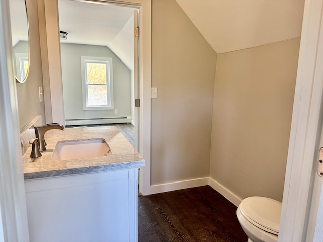 338 River Rd, Bucksport, ME 04416 - half bath featuring baseboard heating, lofted ceiling, vanity, wood finished floors, and toilet