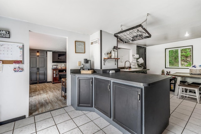 54 Old Canton Rd, Dixfield, ME 04224 - kitchen featuring dark countertops, light tile patterned floors, a peninsula, and a sink