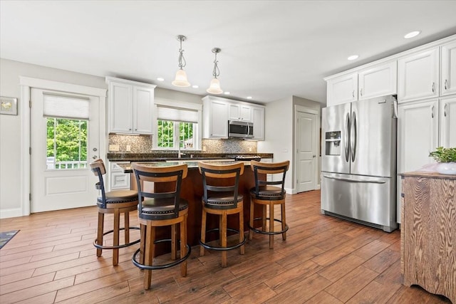 64 New Settlement Rd, Hiram, ME 04041 - kitchen featuring stainless steel appliances, decorative backsplash, white cabinets, a kitchen bar, and recessed lighting
