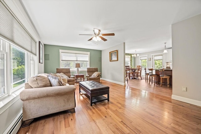 64 New Settlement Rd, Hiram, ME 04041 - living room with a baseboard heating unit, ceiling fan, light wood finished floors, and a chandelier