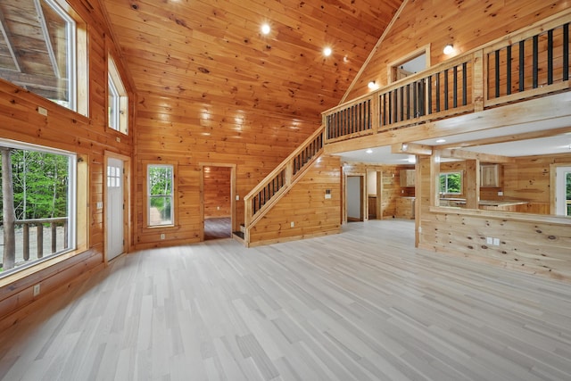 545 Back Rd, Skowhegan, ME 04976 - unfurnished living room with wooden walls, stairs, wood finished floors, and high vaulted ceiling