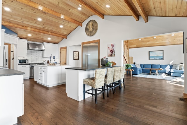 134 Zakelo Rd, Harrison, ME 04040 - kitchen featuring wall chimney range hood, high quality appliances, dark wood-type flooring, a center island with sink, and white cabinetry
