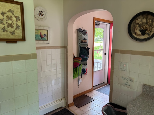 16 Steamboat St, Calais, ME 04619 - entrance foyer with tile walls, a baseboard heating unit, light tile patterned flooring, arched walkways, and wainscoting