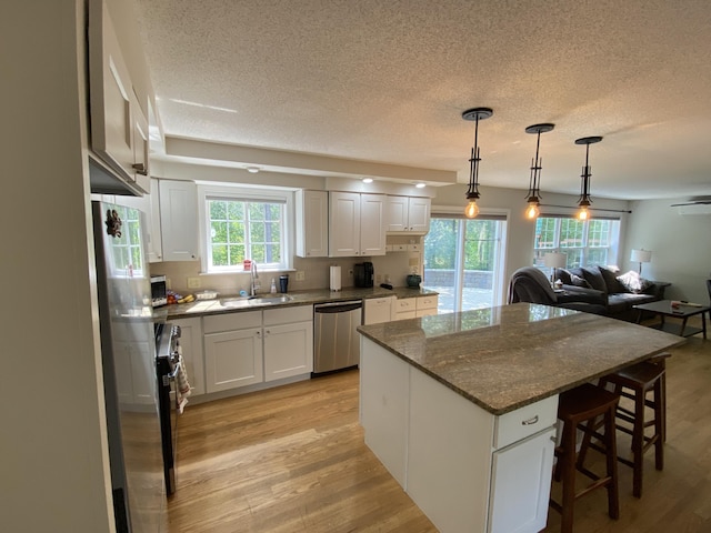 12 Cromwell Dr, Orono, ME 04473 - kitchen with appliances with stainless steel finishes, a textured ceiling, light wood-style floors, a center island, and white cabinets