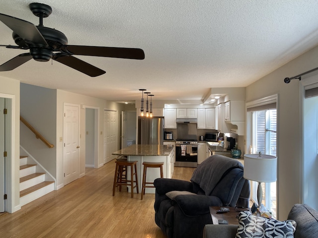 12 Cromwell Dr, Orono, ME 04473 - living area featuring a textured ceiling, ceiling fan, stairway, and light wood-type flooring