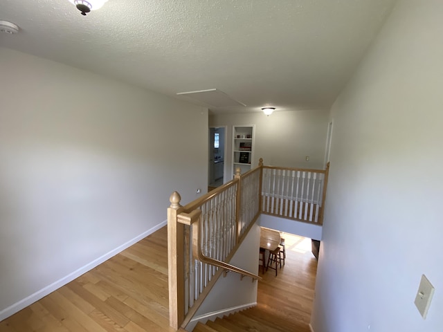 12 Cromwell Dr, Orono, ME 04473 - stairway featuring attic access, wood finished floors, a textured ceiling, and built in shelves