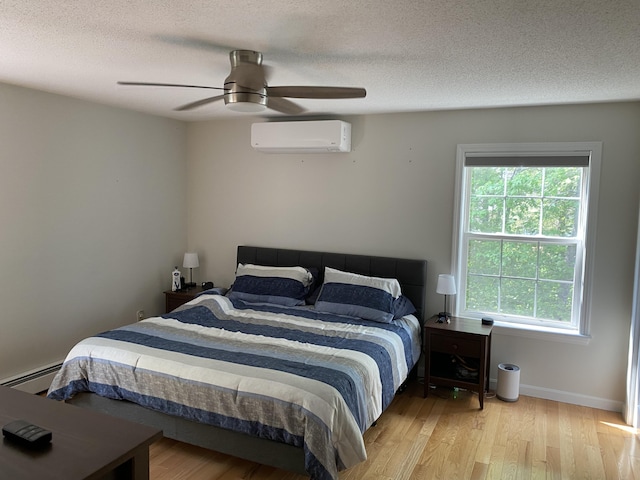 12 Cromwell Dr, Orono, ME 04473 - bedroom with an AC wall unit, wood finished floors, a textured ceiling, and ceiling fan