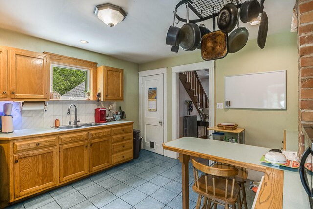 121 Bolton St, Portland, ME 04102 - kitchen with a sink, light countertops, decorative backsplash, light tile patterned floors, and brown cabinets