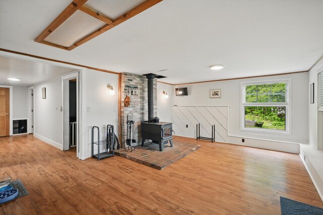 14 Greenleaf Ln, Monmouth, ME 04259 - unfurnished living room featuring a wood stove, wood finished floors, ornamental molding, and baseboards