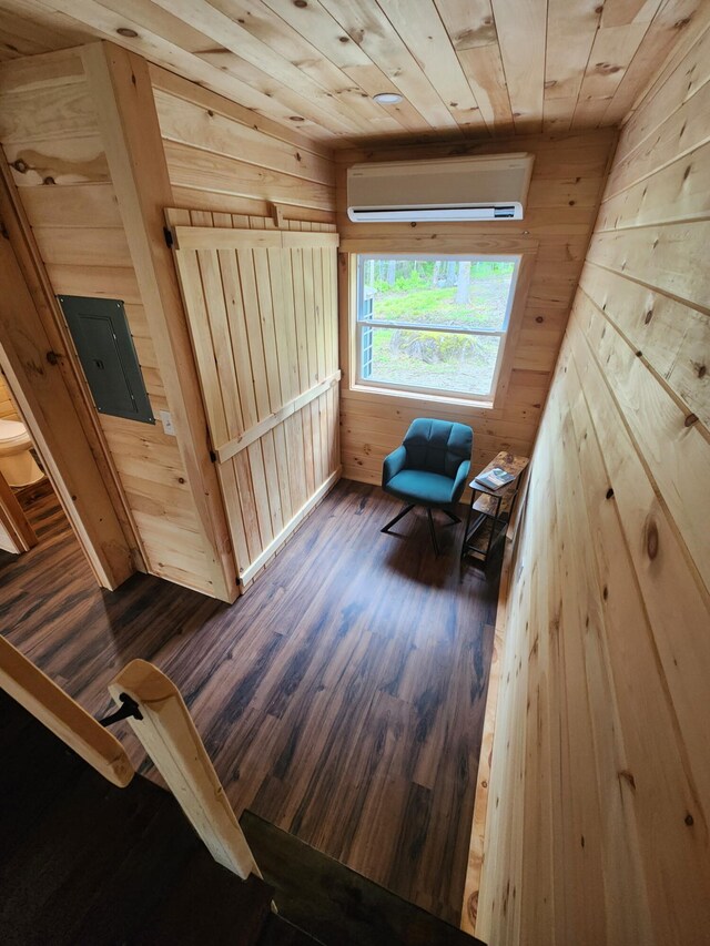 105 Gales Rd, Abbot, ME 04406 - living area featuring a wall unit AC, wood walls, electric panel, wood finished floors, and wooden ceiling