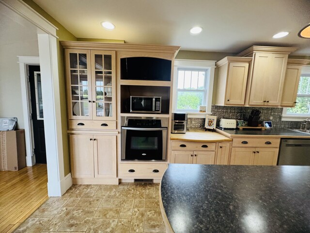 228 Mcburnie Rd, Presque Isle, ME 04769 - kitchen featuring appliances with stainless steel finishes, tasteful backsplash, dark countertops, light brown cabinets, and glass insert cabinets