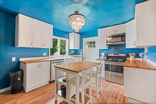 194 Larkin St, Bangor, ME 04401 - kitchen with appliances with stainless steel finishes, butcher block counters, white cabinetry, and light wood-style floors