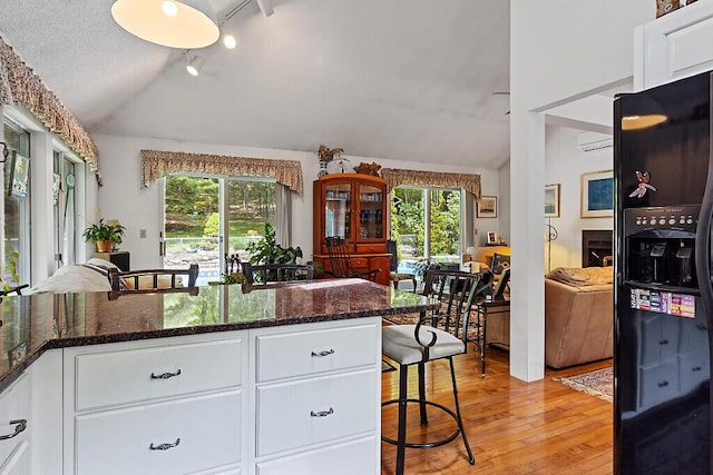 363 Winthrop Center Rd, Winthrop, ME 04364 - kitchen with black fridge with ice dispenser, lofted ceiling, healthy amount of natural light, an AC wall unit, and light wood finished floors