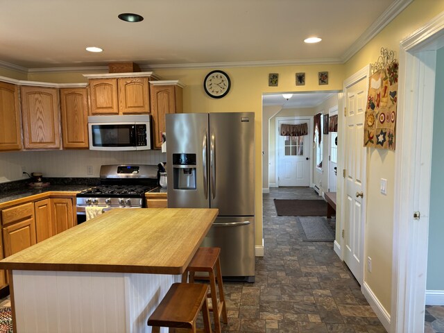 25 Raccoon Rd, Cushing, ME 04563 - kitchen with stainless steel appliances, crown molding, a kitchen breakfast bar, dark stone finish flooring, and recessed lighting