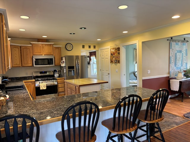 25 Raccoon Rd, Cushing, ME 04563 - kitchen with appliances with stainless steel finishes, crown molding, dark wood-style floors, a peninsula, and recessed lighting
