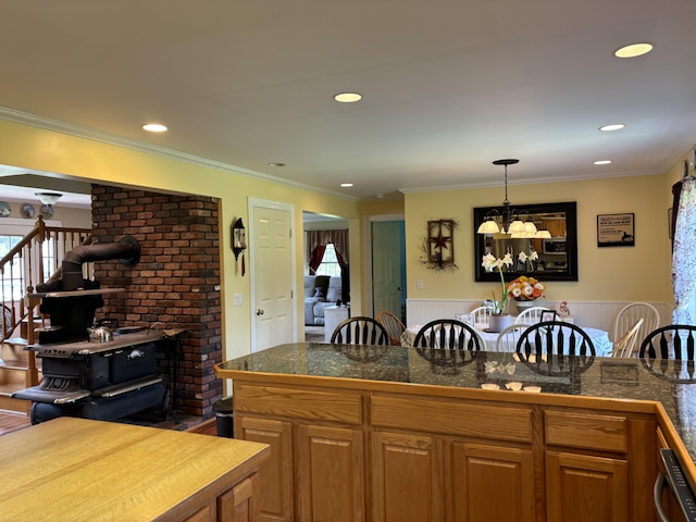 25 Raccoon Rd, Cushing, ME 04563 - kitchen with tile counters, hanging light fixtures, brown cabinetry, ornamental molding, and a wainscoted wall