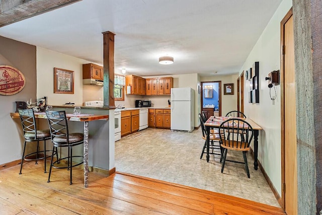 125 Lone Indian Trl, Augusta, ME 04330 - kitchen with white appliances, brown cabinets, a breakfast bar area, a peninsula, and baseboards
