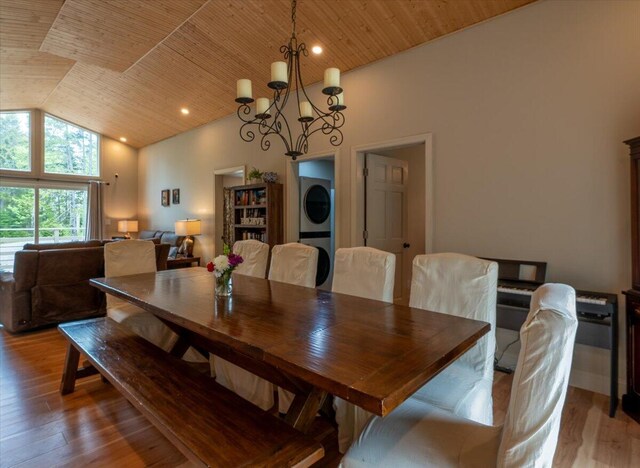 144 Woody Ln, Cushing, ME 04563 - dining area with estacked washer and dryer, wood finished floors, a chandelier, wooden ceiling, and high vaulted ceiling