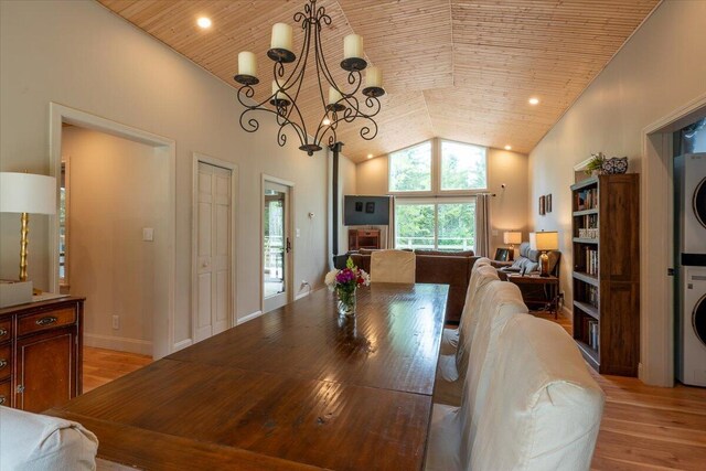 144 Woody Ln, Cushing, ME 04563 - dining area featuring stacked washer / drying machine, light wood-style flooring, high vaulted ceiling, a chandelier, and wooden ceiling