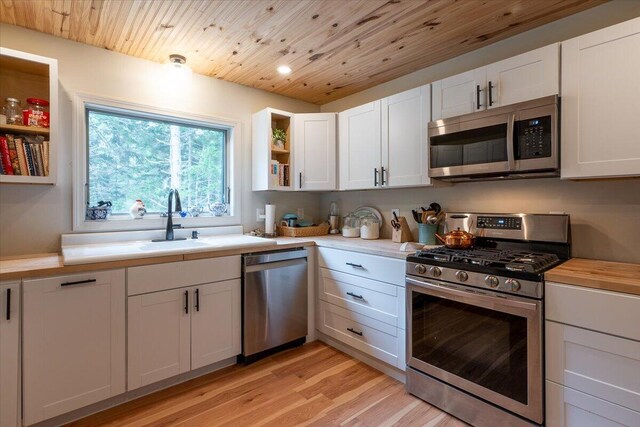 144 Woody Ln, Cushing, ME 04563 - kitchen featuring stainless steel appliances, open shelves, light wood-style floors, white cabinets, and wood ceiling