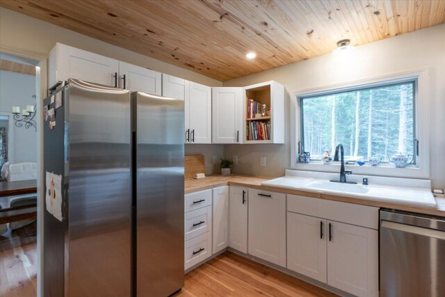 144 Woody Ln, Cushing, ME 04563 - kitchen with stainless steel appliances, a sink, light countertops, white cabinetry, and light wood-style flooring