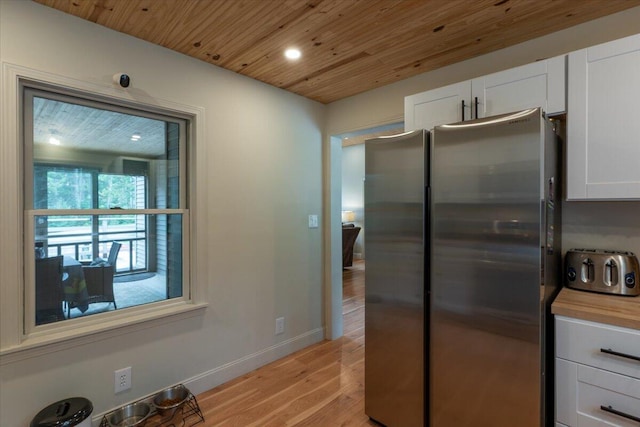 144 Woody Ln, Cushing, ME 04563 - kitchen with freestanding refrigerator, wooden ceiling, light wood-type flooring, white cabinetry, and baseboards
