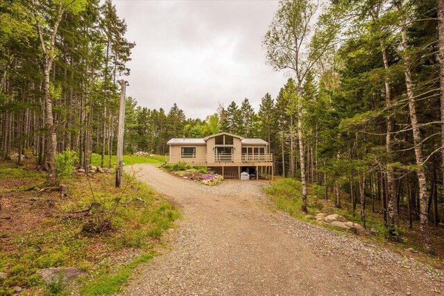 144 Woody Ln, Cushing, ME 04563 - view of front of home with dirt driveway, a view of trees, and a deck