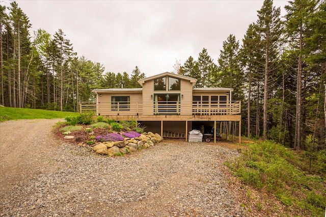 144 Woody Ln, Cushing, ME 04563 - view of front facade featuring driveway, a wooden deck, and a forest view