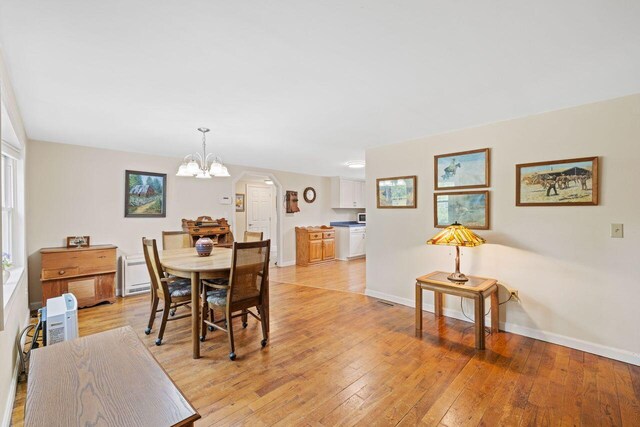 16 Van Buren Dr, Newfield, ME 04095 - dining room with a chandelier, baseboards, light wood-style floors, and arched walkways