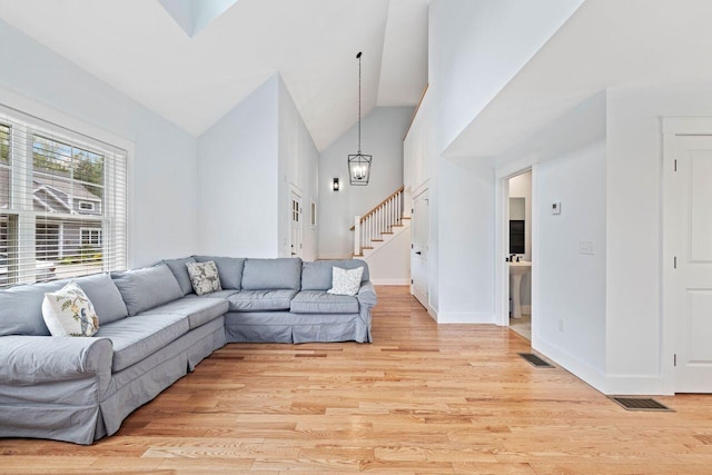 12 Haleys Ct Unit 21, Wells, ME 04090 - living room with stairs, light wood-style floors, high vaulted ceiling, a chandelier, and baseboards