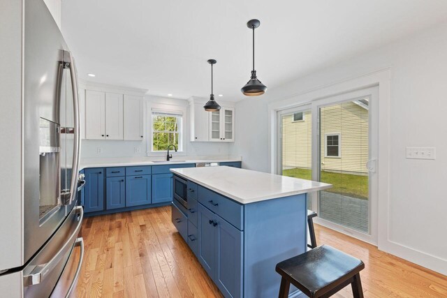 12 Haleys Ct Unit 21, Wells, ME 04090 - kitchen featuring stainless steel appliances, blue cabinets, a sink, a breakfast bar area, and light wood-style floors