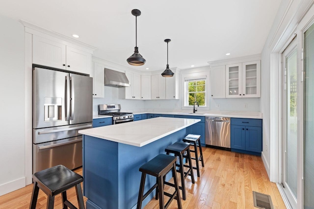 12 Haleys Ct Unit 21, Wells, ME 04090 - kitchen with stainless steel appliances, ventilation hood, blue cabinets, a sink, and a breakfast bar