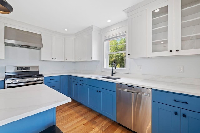 12 Haleys Ct Unit 21, Wells, ME 04090 - kitchen with appliances with stainless steel finishes, wall chimney range hood, a sink, blue cabinetry, and white cabinets