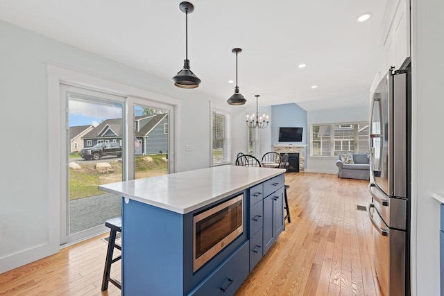 12 Haleys Ct Unit 21, Wells, ME 04090 - kitchen with appliances with stainless steel finishes, blue cabinetry, a kitchen bar, light wood finished floors, and open floor plan