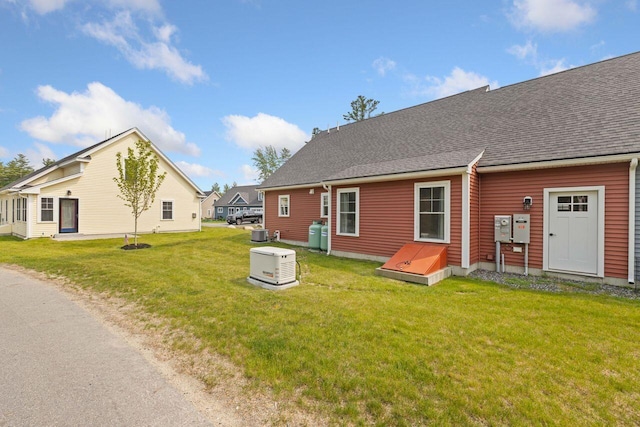 12 Haleys Ct Unit 21, Wells, ME 04090 - back of property featuring a yard, central AC unit, and roof with shingles