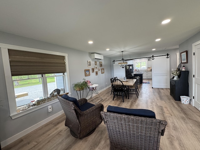588 Mason Bay Rd, Jonesport, ME 04649 - living room featuring a wall unit AC, a barn door, recessed lighting, light wood-style floors, and baseboards