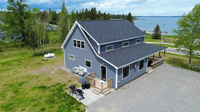 588 Mason Bay Rd, Jonesport, ME 04649 - view of front of property featuring roof with shingles, a deck with water view, a front yard, and a patio area