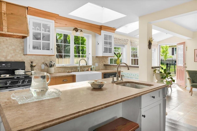 44 Bridge St, Bucksport, ME 04416 - kitchen featuring a sink, a skylight, backsplash, and white cabinets