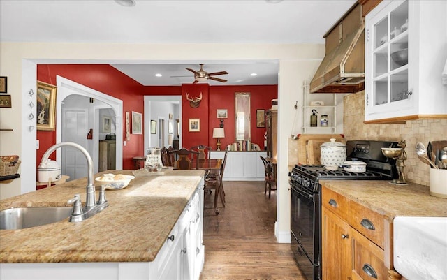 44 Bridge St, Bucksport, ME 04416 - kitchen featuring black gas stove, a sink, wood finished floors, under cabinet range hood, and white cabinetry