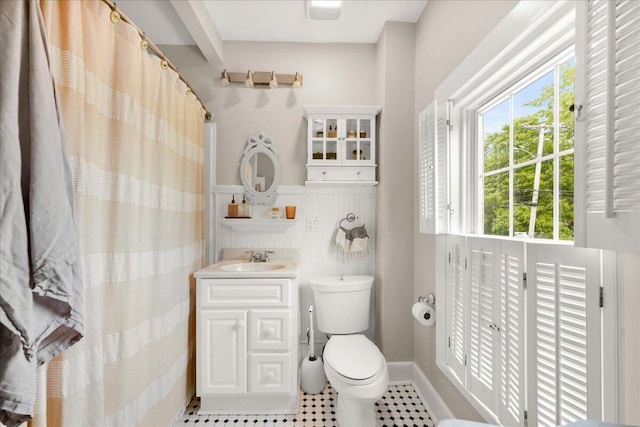 44 Bridge St, Bucksport, ME 04416 - full bathroom featuring toilet, vanity, a wainscoted wall, tile patterned floors, and a shower with shower curtain