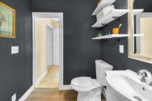 44 Bridge St, Bucksport, ME 04416 - bathroom featuring a sink, toilet, baseboards, and wood finished floors
