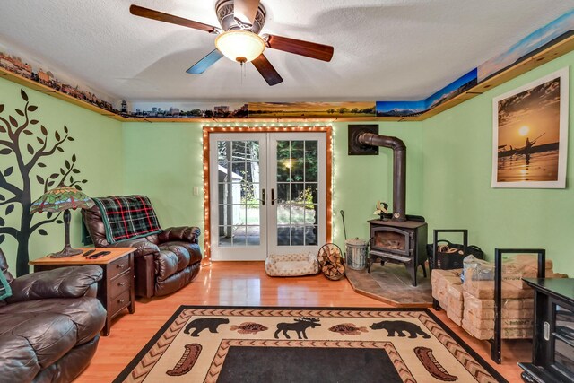 42 Lee Dr, Albion, ME 04910 - living area featuring a wood stove, wood finished floors, french doors, ceiling fan, and a textured ceiling
