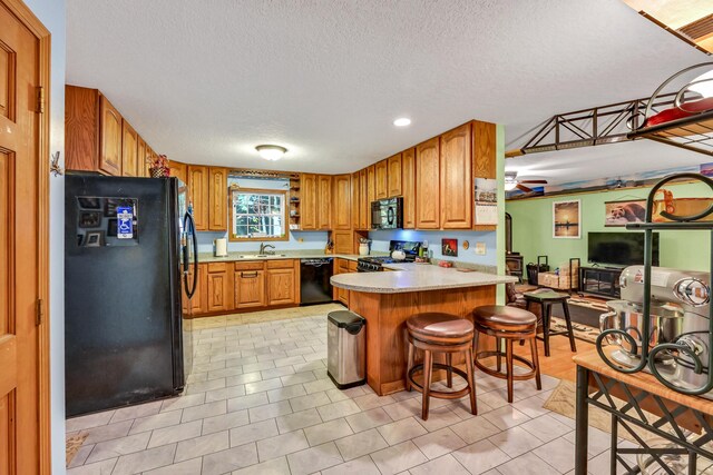42 Lee Dr, Albion, ME 04910 - kitchen featuring black appliances, a peninsula, light countertops, a textured ceiling, and brown cabinetry