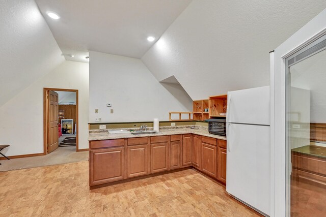 42 Lee Dr, Albion, ME 04910 - kitchen with freestanding refrigerator, a sink, lofted ceiling, light colored carpet, and brown cabinets
