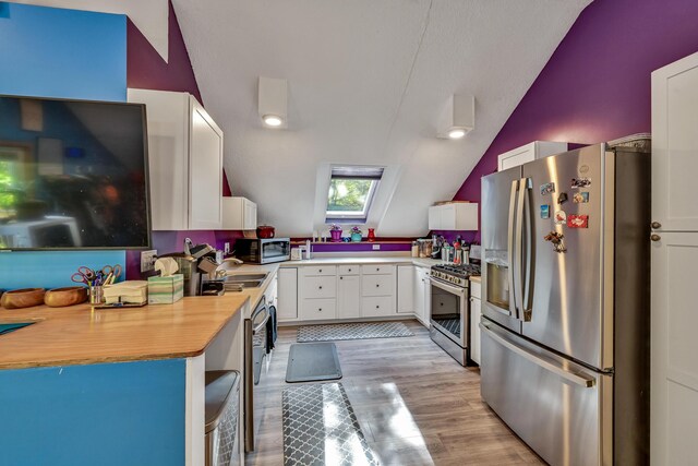 42 Lee Dr, Albion, ME 04910 - kitchen featuring stainless steel appliances, vaulted ceiling, white cabinets, light countertops, and light wood-style floors