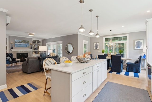 18 Forest Hill Ln, Kennebunk, ME 04043 - kitchen featuring plenty of natural light, a glass covered fireplace, white cabinets, crown molding, and a kitchen bar