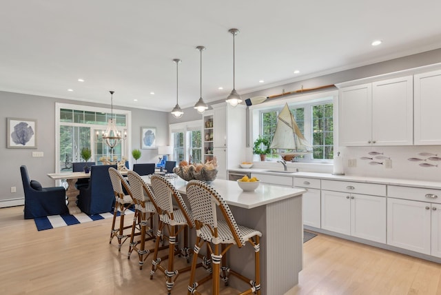 18 Forest Hill Ln, Kennebunk, ME 04043 - kitchen featuring ornamental molding, a sink, light wood-style flooring, white cabinets, and light countertops
