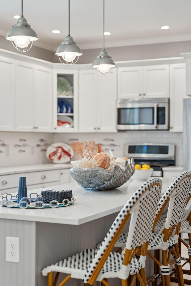 18 Forest Hill Ln, Kennebunk, ME 04043 - kitchen with stainless steel microwave, light countertops, white cabinetry, tasteful backsplash, and hanging light fixtures